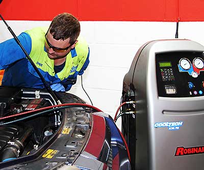 air conditioning expert repairing and regassing a car air con system