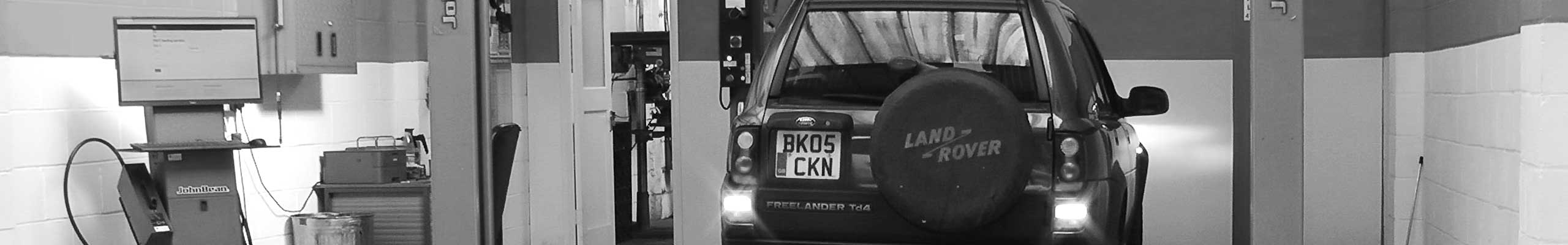 very classy black and white expert photo of excels mot testing bay with a land rover part way through testing