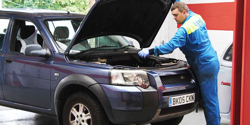 mechanic checking a land rover cars electrical systems with bonnet up for its annual mot test