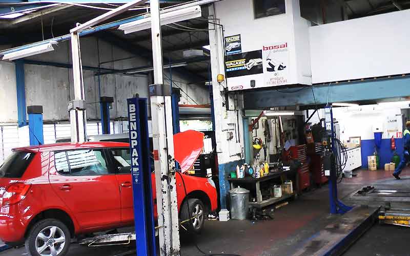 excel automotives car repair garage inside with cars on ramps and mechanics working